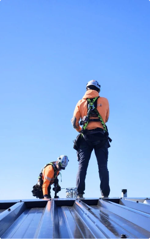Dois trabalhadores com EPI em telhado metálico durante trabalho em altura