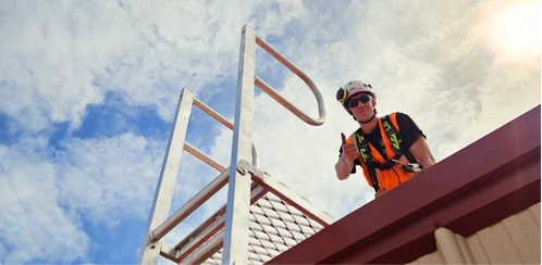 Profissional com EPI em escada marinheiro, indicando equipe habilitada e documentada para instalação.
