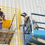 Técnicos realizando instalação em plataforma elevatória, com foco em montagem precisa e integração da linha de vida.