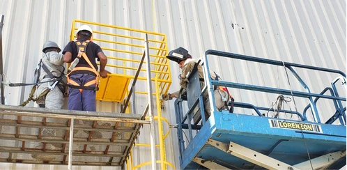 Técnicos realizando instalação em plataforma elevatória, com foco em montagem precisa e integração da linha de vida.
