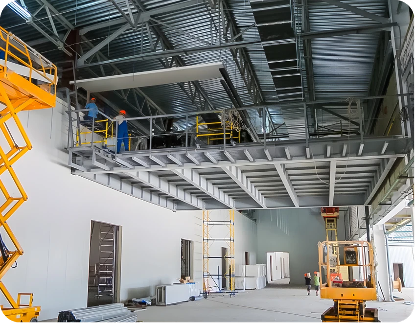 Montagem de mezanino estrutural metálico em galpão industrial com trabalhadores e plataforma elevatória.