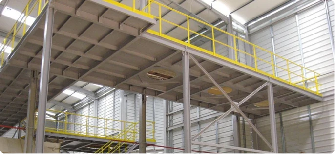 Mezanino estrutural de grande vão em aço com guarda-corpo amarelo e escada de acesso em ambiente industrial.